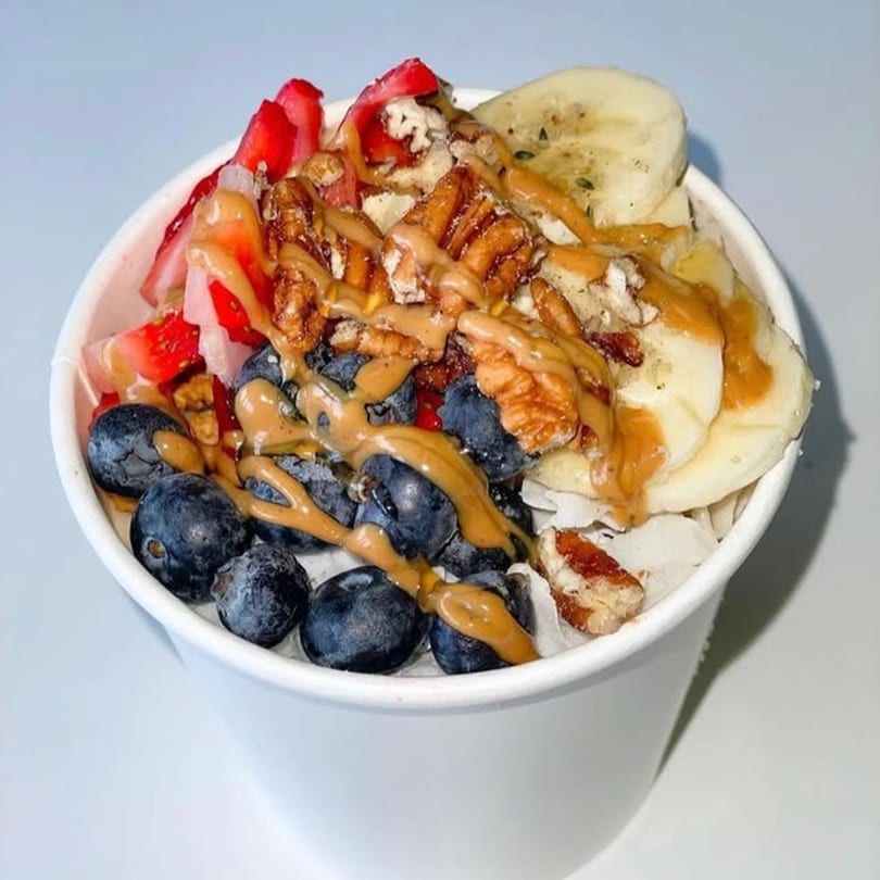 A Vytal Nutrition smoothie bowl with blueberries, strawberries, bananas, pecans, and peanut butter drizzle.