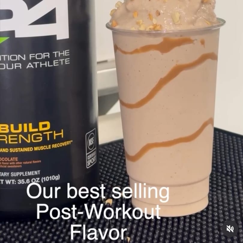 A Vytal Nutrition chocolate protein smoothie with caramel drizzle and nuts next to a protein powder container.